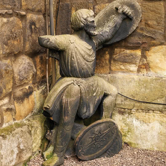 An Alnwick Castle Gnome hiding behind a wall